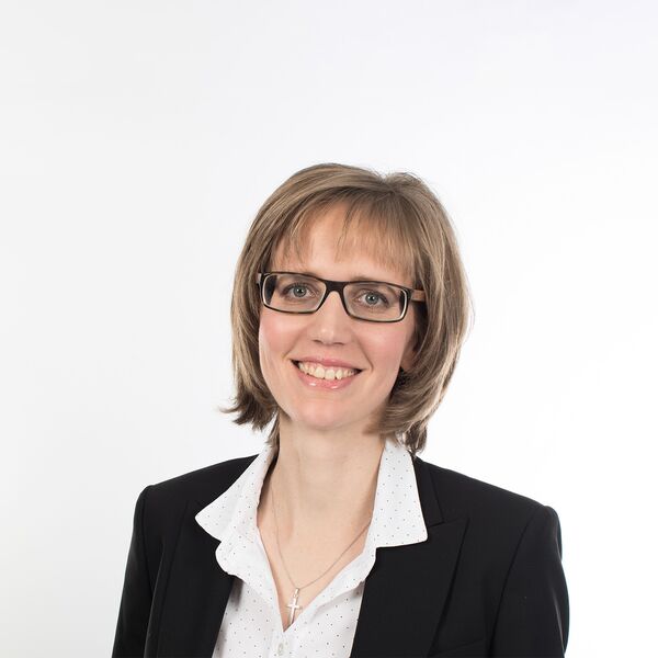 Das Bild zeigt eine Frau mit Anzug und Brille