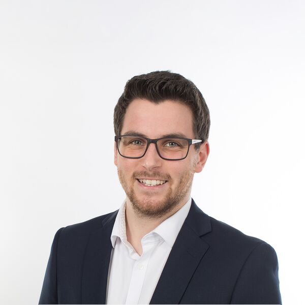 Das Bild zeigt einen Mann mit Anzug und Brille